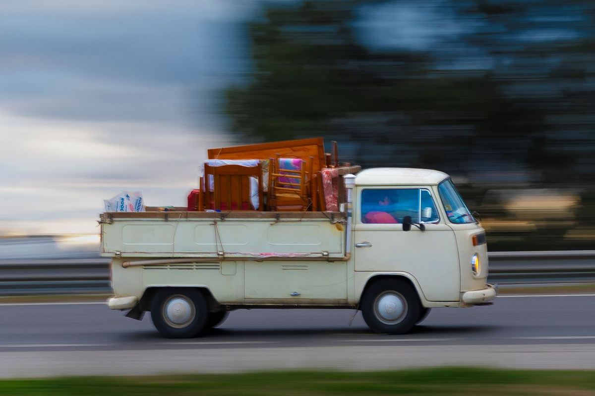 A van carrying furniture along a road, shot in motion